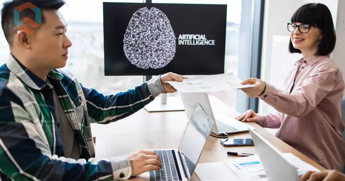 Dua orang berdiskusi dengan latar belakang layar bertuliskan Artificial Intelligence